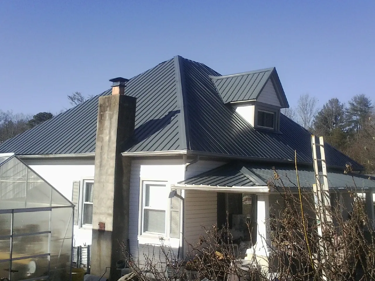 Dark blue standing seam metal roof on a white farmhouse with dormer — Slate & Tile Roof Repair by Roofing Brothers in Rising Fawn