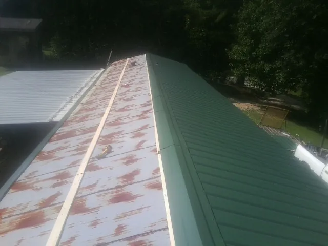 Old rusted panels beside newly installed green metal roofing — Wind Damage Roof Repair by Roofing Brothers in Rising Fawn