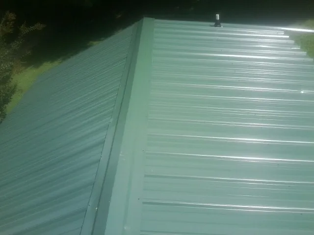 New green metal panels meeting at the ridge of a roof — Flat Roof Repair work by our crew in Rising Fawn