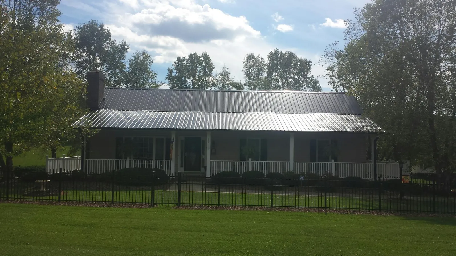Gray metal roof on a brick ranch with a full width front porch — Gutter Guard Installation work by our crew in Rising Fawn