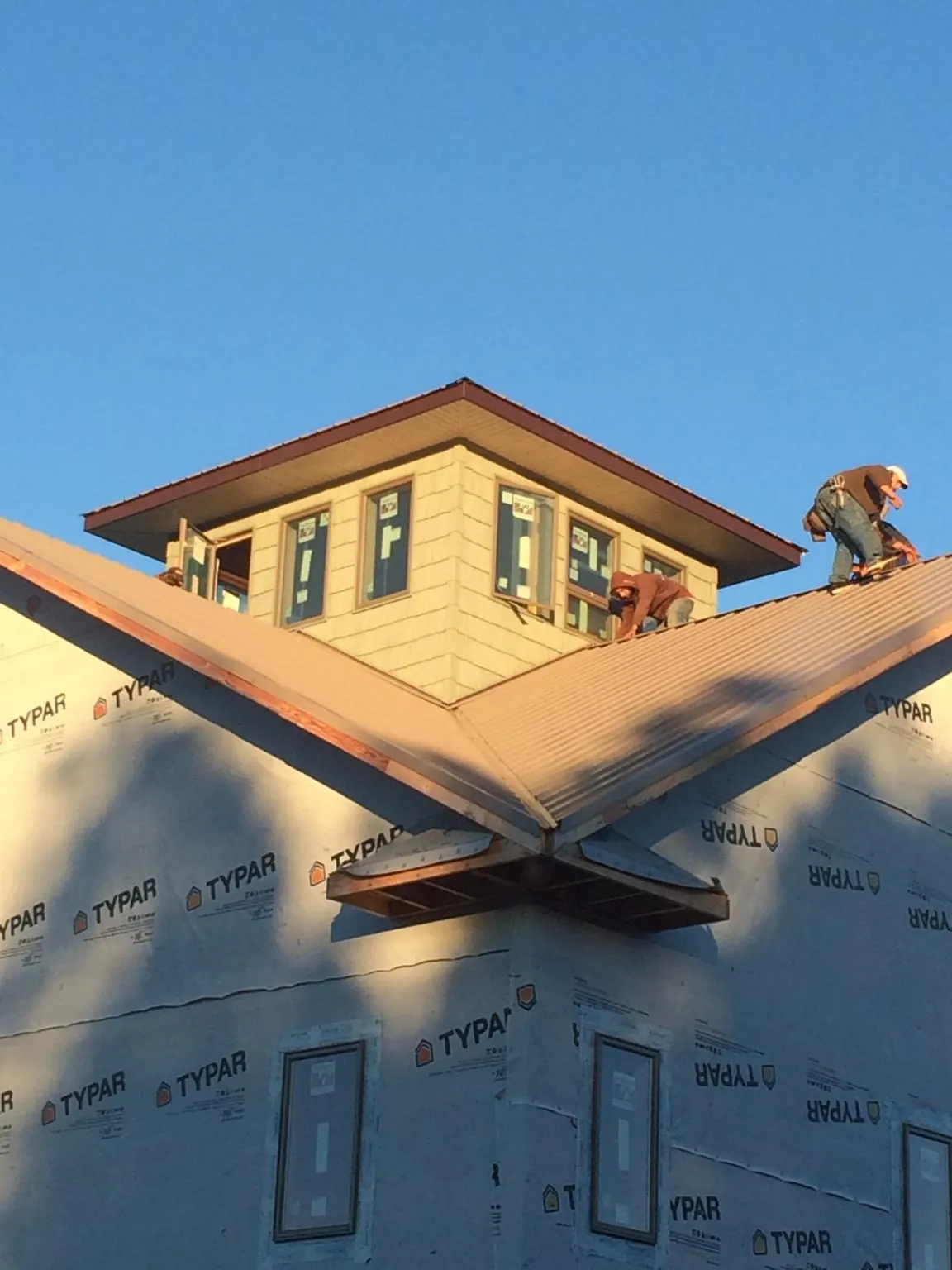 Roofers working around a rooftop cupola on a new metal roof at sunset — Roof Waterproofing in Rising Fawn by Roofing Brothers